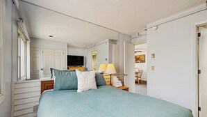 A bedroom with a bed, a television, a lamp, and a chair.