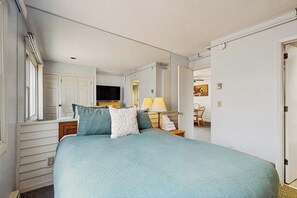 A bedroom with a bed, a television, a lamp, and a chair.