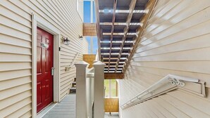 A narrow staircase with a red door at the top, wooden railings, and a skylight.