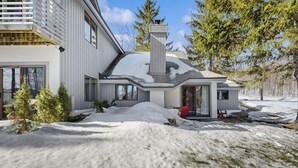 A modern house with a snow-covered roof, a chimney, and a small porch. - Recently updated home with shared hot tub, pool, and easy ski access (Killington)