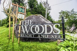 Ein großer Felsen mit der Aufschrift 'The Woods Resort and Spa', umgeben von viel Grün.