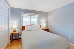 Un dormitorio con una cama, dos mesitas de noche con lámparas, una ventana y una puerta.