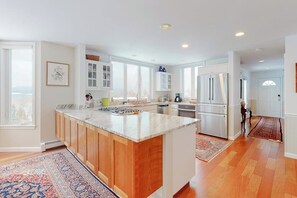 A modern kitchen with a large island, white cabinetry, and a view to the outside.