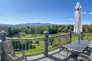 Una terraza con mobiliario exterior, vista a un paisaje montañoso y un pilar de piedra.