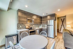 A modern kitchen with a central island, stainless steel appliances, and a dining area with a round table and chairs. - Newly remodeled ski condo near bus to slopes with free WiFi & full kitchen (Killington)