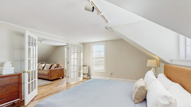 Ein Schlafzimmer mit einem Bett, einem Schminktisch, einem Sofa und einem Deckenventilator.