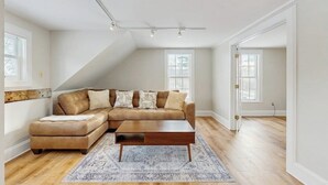 Ein geräumiges Wohnzimmer mit einem Ecksofa, einem Couchtisch und einem gemusterten Teppich.