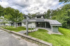 A modern building with a sloped roof, a covered entrance, and a small adjacent structure. - Resort townhome with on-site pool, hot tub & easy ski access (Killington)