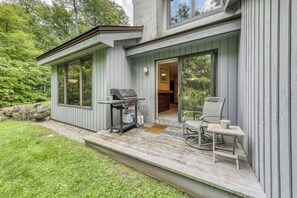 A modern house with a deck, a barbecue, and a dining area with chairs and a table. - Resort townhome with on-site pool, hot tub & easy ski access (Killington)