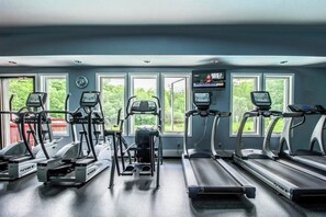 A gym with treadmills, elliptical machines, and a TV screen. - Ski-In/ski-out condo with views, pool, hot tubs, gym & tennis access (Killington)