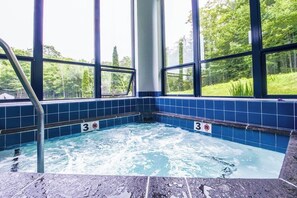 Ein Whirlpool mit Blick auf einen Wald durch große Fenster.