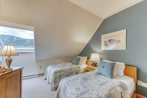 Ein Schlafzimmer mit zwei Betten, einem Schreibtisch, Lampen und einem Fenster mit Blick.