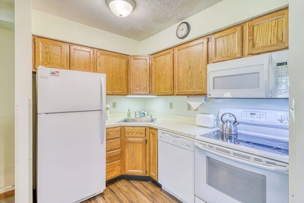Una cocina con armarios de madera, un refrigerador, un microondas, una estufa y un lavavajillas.