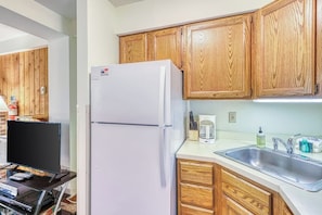 Una cocina con armarios de madera, un refrigerador blanco, una cafetera y un lavabo.