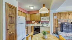 Une cuisine avec des meubles en bois, un four à micro-ondes, une cuisinière et une table à manger avec des chaises.
