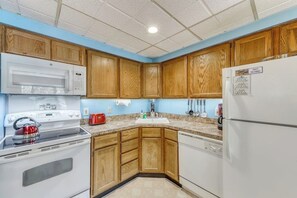Una cocina con armarios de madera, electrodomésticos blancos y una pared de acento azul.