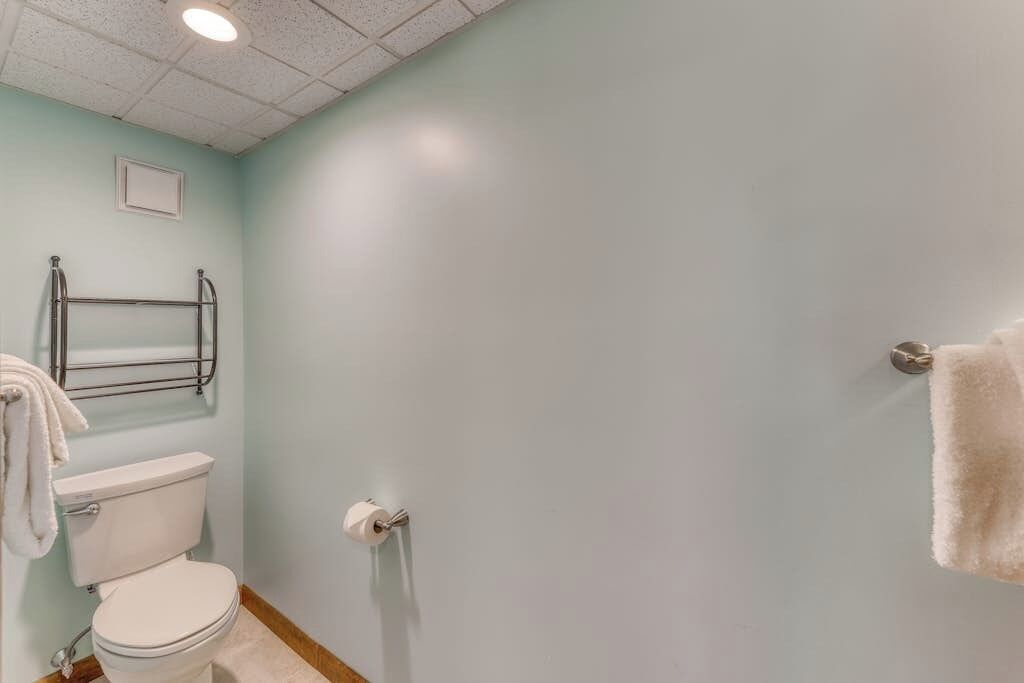 A bathroom with a toilet, towel rack, and a shower area.