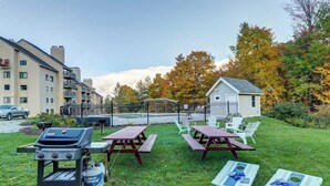 Un espacio al aire libre con césped, mesas de picnic y una parrilla.