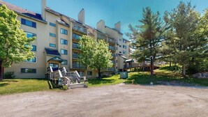 Hotel de varios pisos con escaleras exteriores, una zona cubierta y un estacionamiento de tierra.