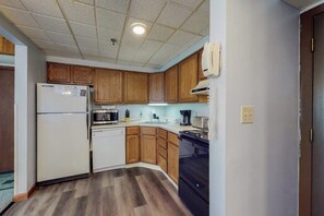 A kitchen with wooden cabinets, a refrigerator, a microwave, a dishwasher, and a stove. - Mountain view condo with full kitchen and free WiFi (Killington)