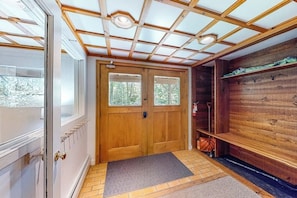 Eine Holztür mit Glasscheibe, eine Bank mit Handtuch und eine Holzwand mit Haken.