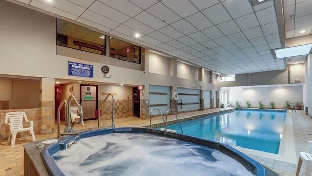 Una piscina interior con jacuzzi, un balcón en el segundo piso y un cartel que indica un complejo de montaña.