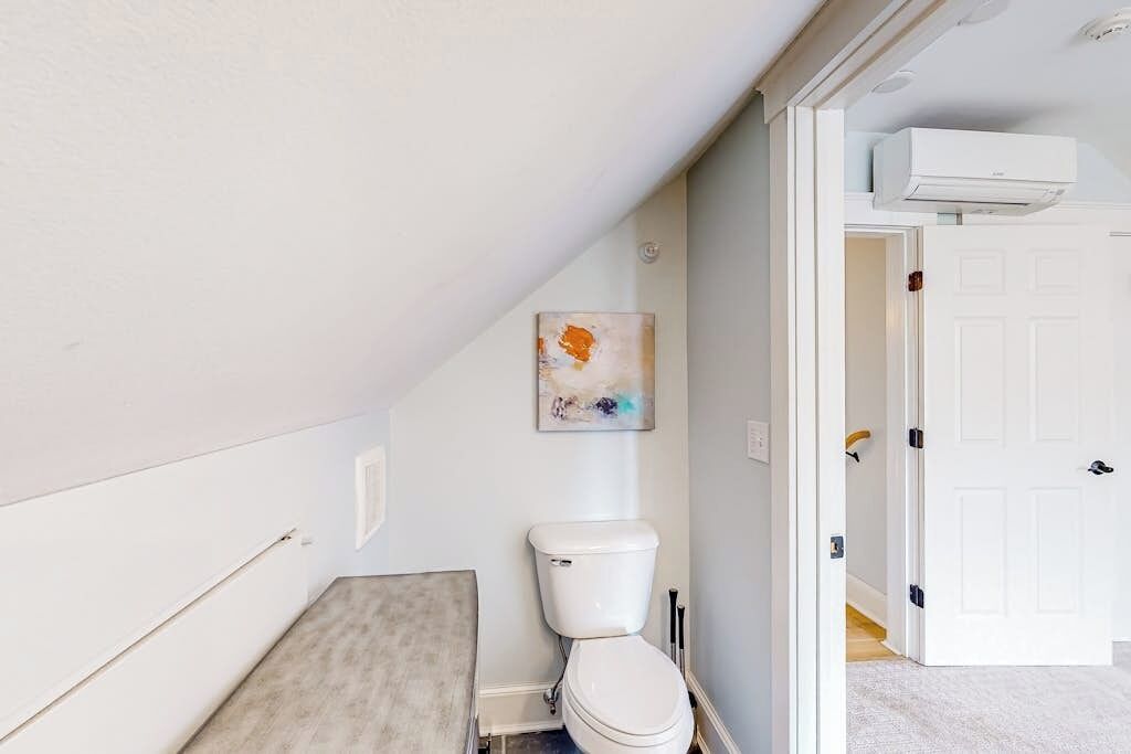 A bathroom with a toilet, a shower area, and a door leading to another room.