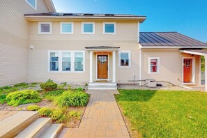 Une maison à deux étages avec une entrée à l’avant, un petit porche et une pelouse bien entretenue.