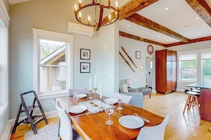 A dining area with a wooden table set for four, a chandelier, and a staircase leading to an upper level.