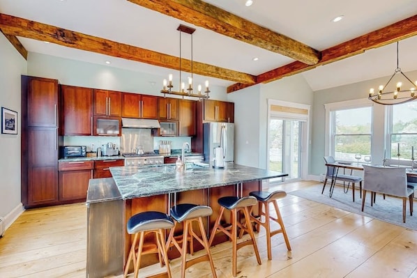 A spacious kitchen with wooden cabinets, a large island with bar stools, and a dining area with a table and chairs.