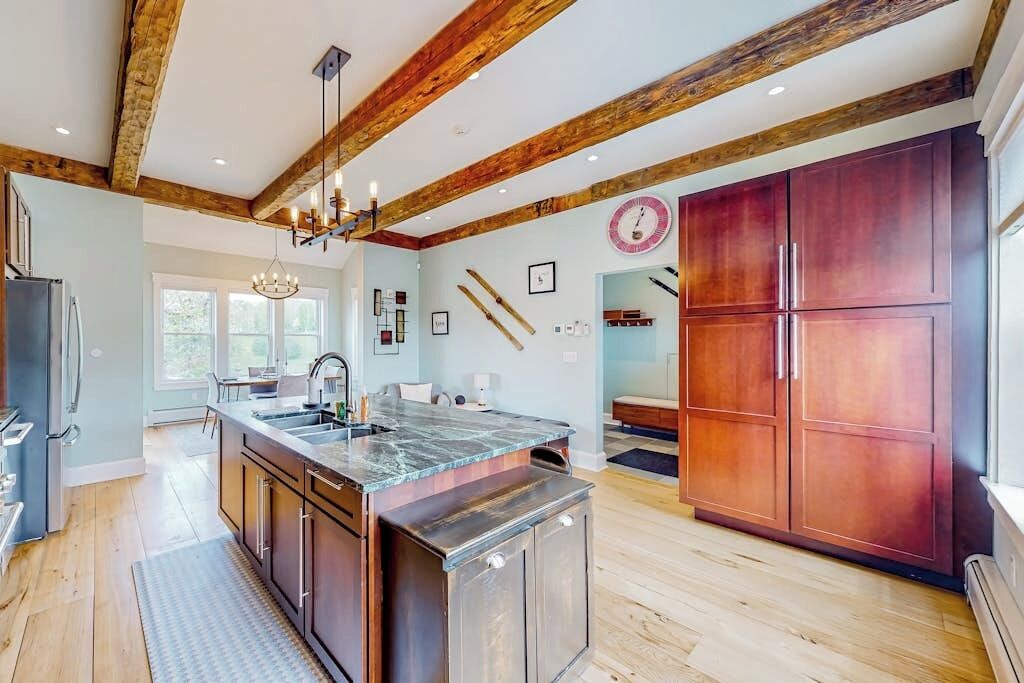 Una cocina amplia con vigas de madera, una isla grande y un horno empotrado.