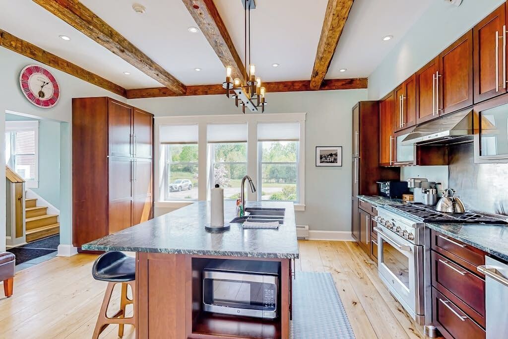 A kitchen with wooden cabinets, a central island, a built-in microwave, and a stainless steel range hood.