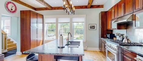 A kitchen with wooden cabinets, a central island, a built-in microwave, and a stainless steel range hood.