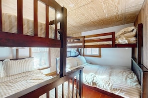 Ein Schlafzimmer mit Etagenbetten, Holzbalken und einer schrägen Decke.