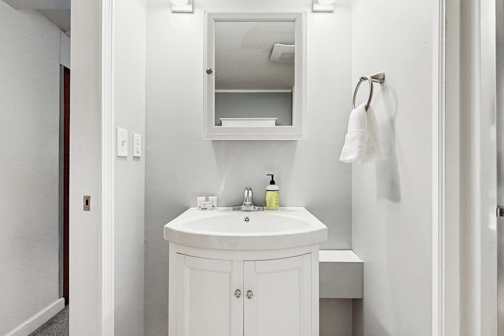 Een badkamer met een witte wastafel, spiegel en handdoekhouder.