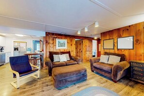 Ein gemütliches Wohnzimmer mit einer Holzwand, einem Sofa, einem Sessel und einem Couchtisch.