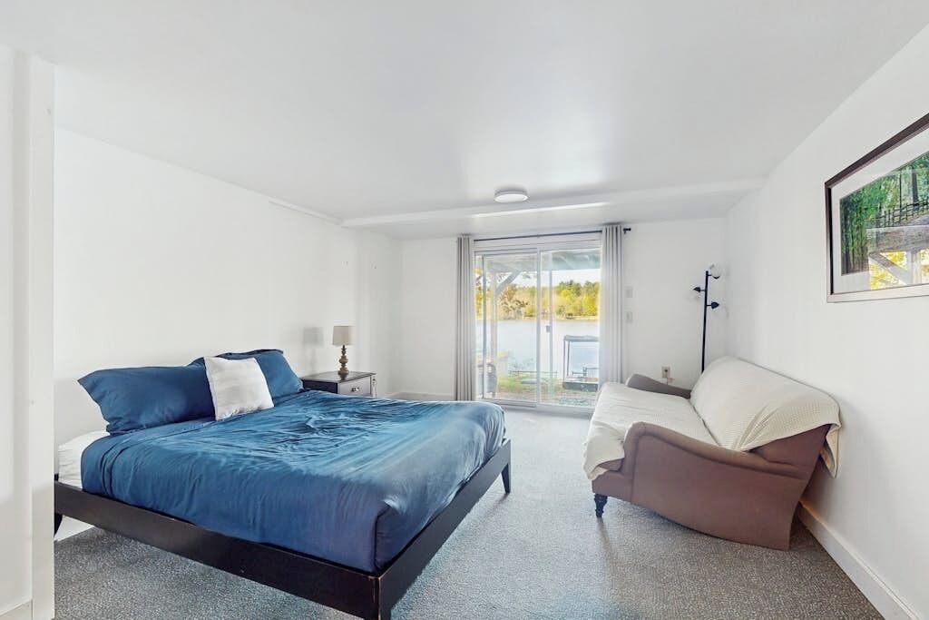 Une chambre à coucher avec un lit, une chaise, une table de chevet et une fenêtre donnant sur un beau paysage.