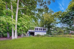 A house with a deck and a staircase leading to an upper level. - Cozy home with lake front property, views, bbq, dock, kayak, wifi, TV, w/d (Castleton)