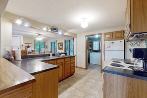 A kitchen with wooden cabinets, a central island, and a stove. - Cozy home with lake front property, views, bbq, dock, kayak, wifi, TV, w/d (Castleton)