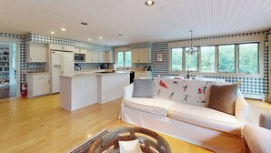 Een moderne keuken met witte kasten, een centraal eiland en een zithoek met een witte bank.