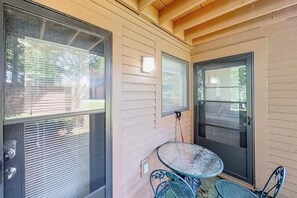 Eine überdachte Veranda mit Tisch und Stühlen, großen Fenstern und einer Tür.