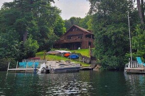Eine Holzhütte mit einem Steg, einem Boot und einem überdachten Bereich mit Sitzgelegenheiten.