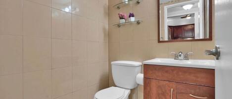 A bathroom with a toilet, a sink, wooden cabinets, and a mirror.