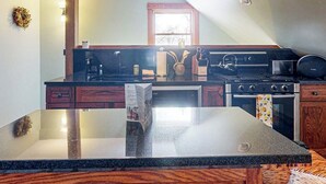 A kitchen with a granite countertop, wooden cabinets, a stove, and a window. - Spacious studio, dog-friendly, close to recreation, central a/c, TV, wifi (Barnard)