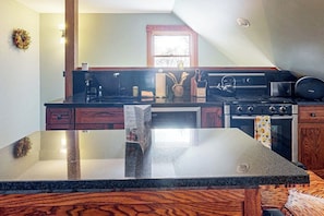 A kitchen with a granite countertop, wooden cabinets, a stove, and a window. - Spacious studio, dog-friendly, close to recreation, central a/c, TV, wifi (Barnard)
