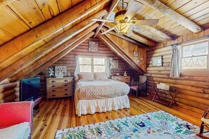 A log cabin bedroom with a bed, dresser, and a ceiling fan. - Cozy log cabin & loft, close to recreation, dog-friendly, bbq, balcony, a/c, w/d (Barnard)