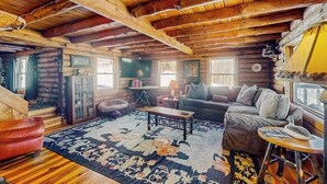 Een vakantiehuisje interieur met houten plafond, een bank, een bijzettafeltje en een vloerkleed.