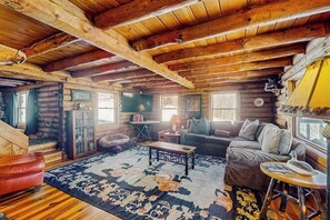 A log cabin interior with a wooden ceiling, a sofa, a coffee table, and a rug. - Cozy log cabin & loft, close to recreation, dog-friendly, bbq, balcony, a/c, w/d (Barnard)