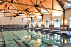 Una piscina interior amb bigues de fusta, vials delimitats i gandules.