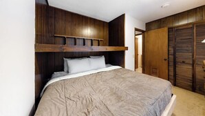 Un dormitorio con cama, cabecero de madera y un armario.